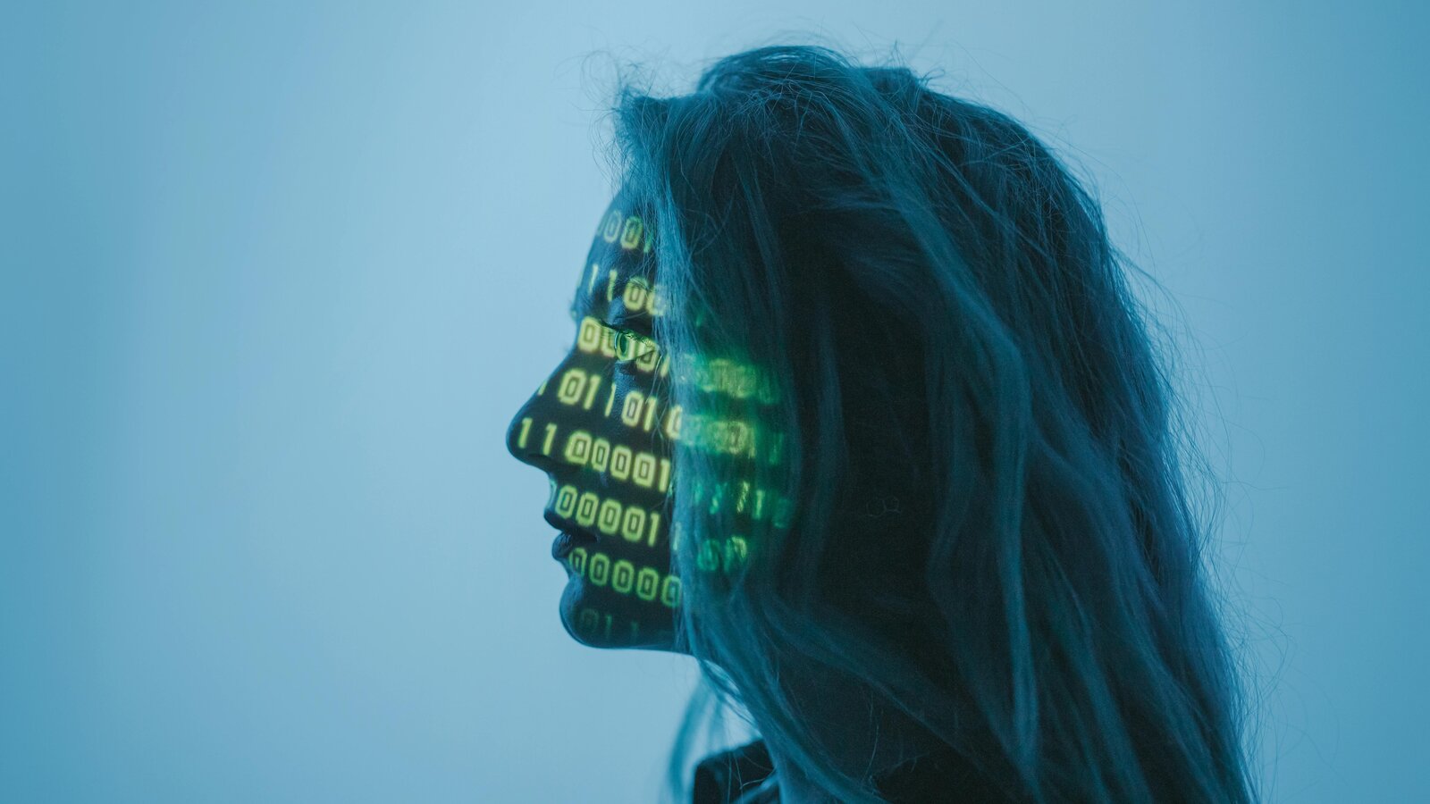 Mujer concentrada con código binario proyectado en el rostro representando inteligencia artificial procesando información